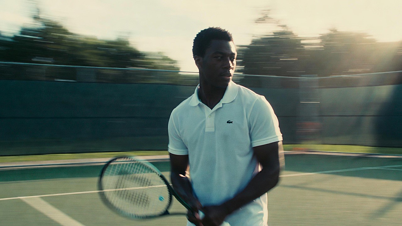 A lush green tennis court representing the brand's athletic heritage